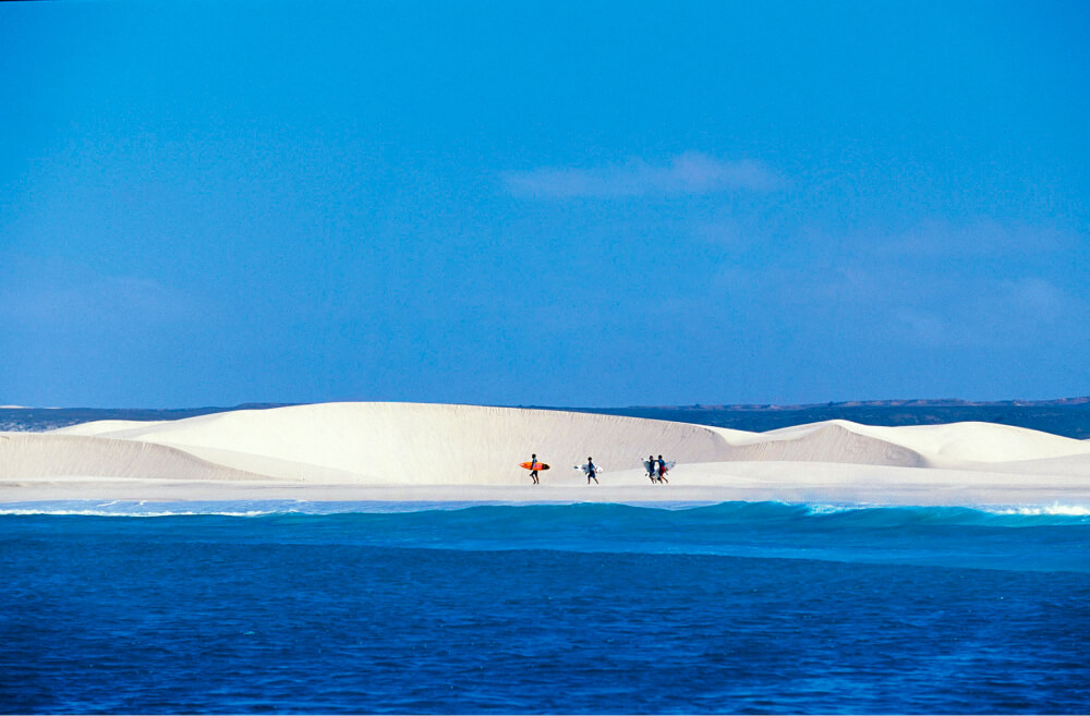 Surfers walking in front of a sand dune