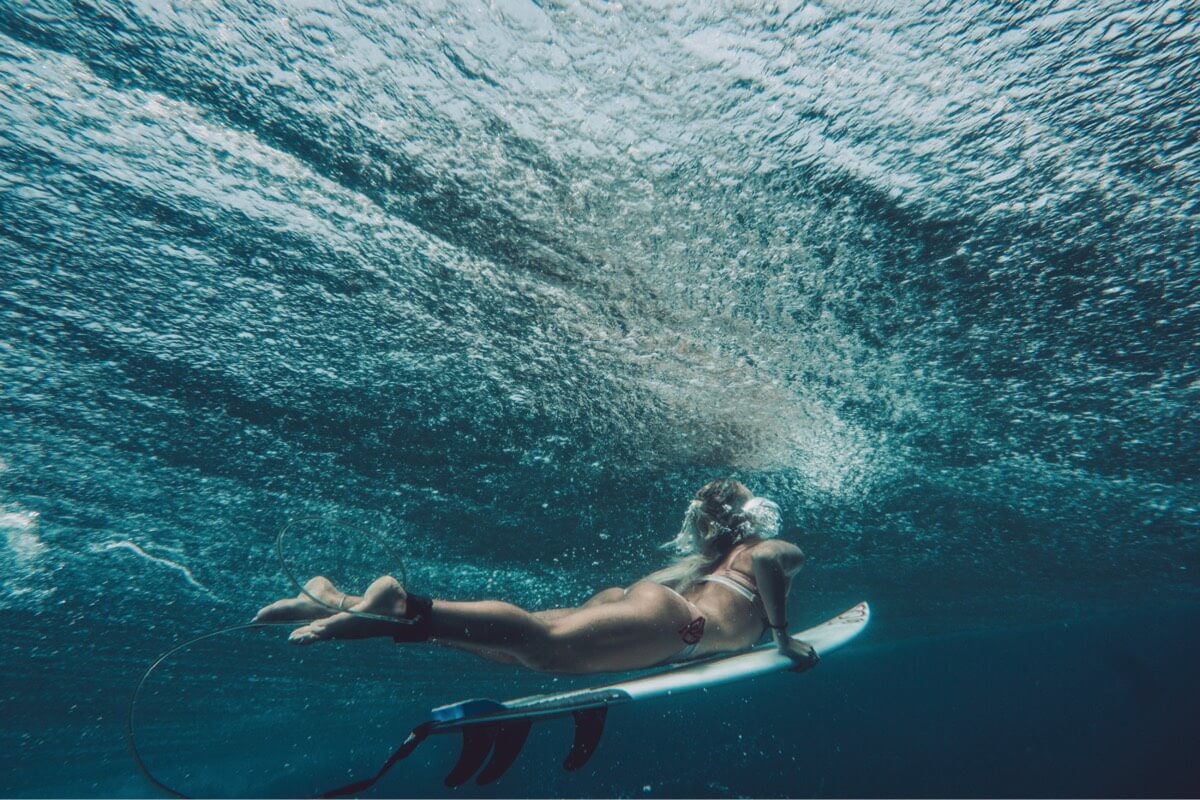 Surfer, Elle Sampiere duck diving underwater on a surfboard. Photo by Camille Robiou du Pont