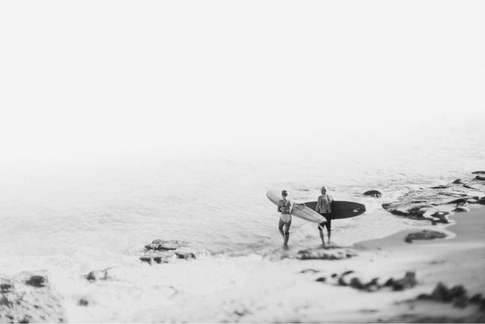 An erderly couple on the beach with surfboards