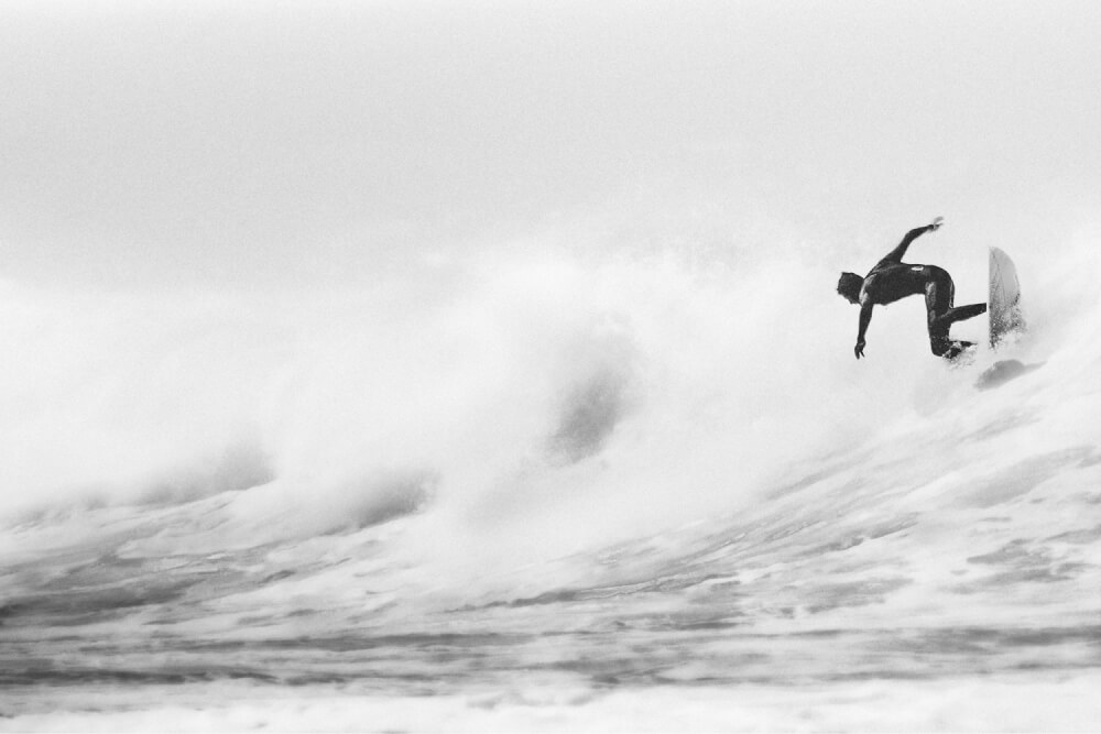 Black and white photo of a surfer riding a wave