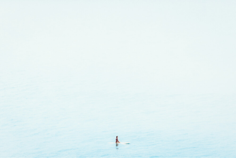 Female surfer sitting on her surfboard, alone in the ocean