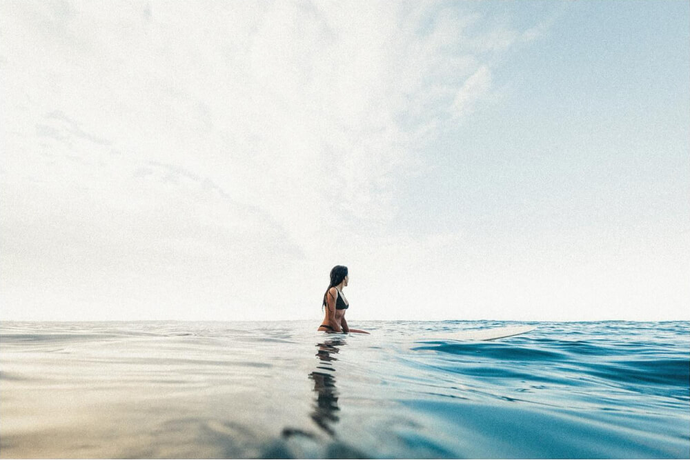 Female surfer sitting on her surfboard