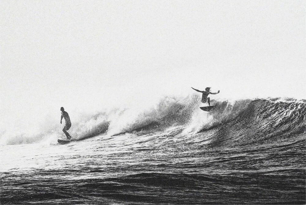 Two surfers riding a wave