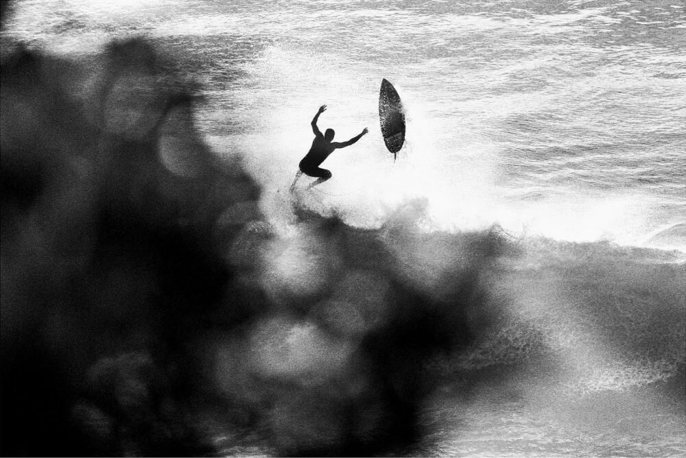 Silhouette of a surfer bailing on a wave