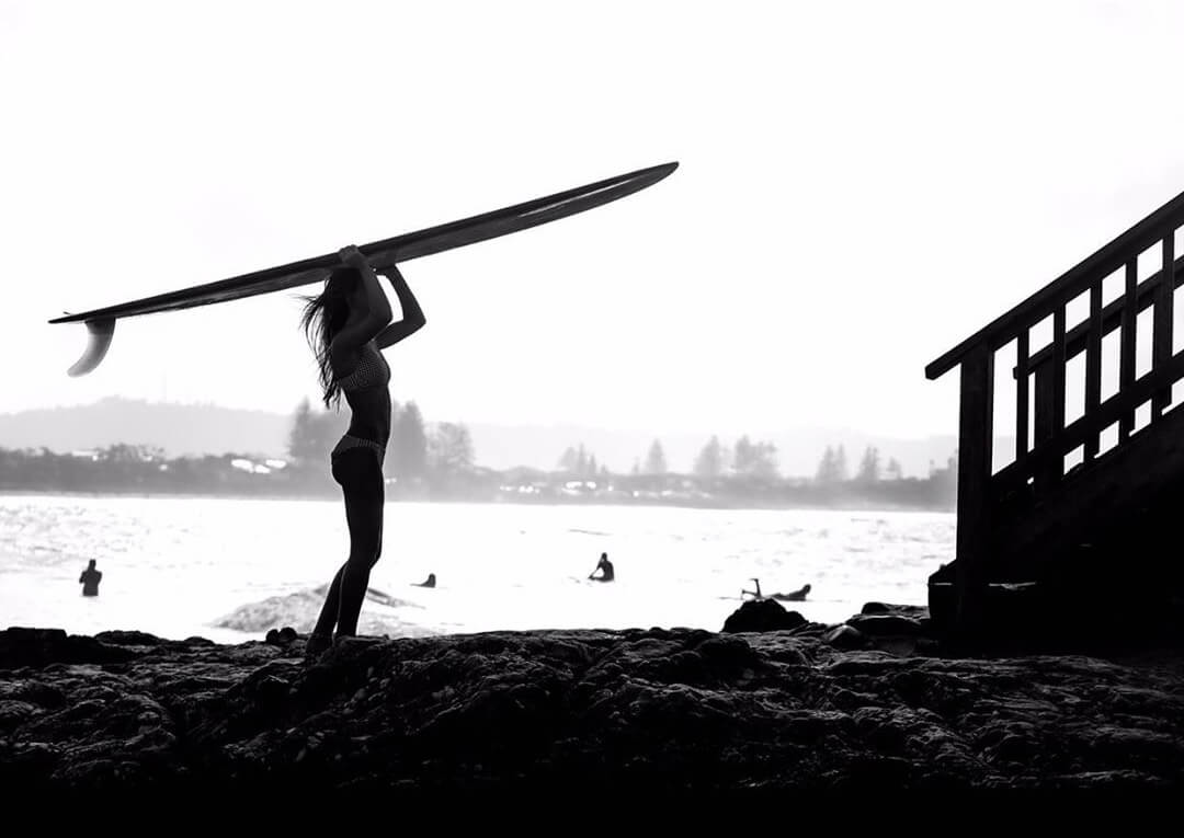 Silhouette of female surfer with surfboard. Photo by Cécilia Thibier