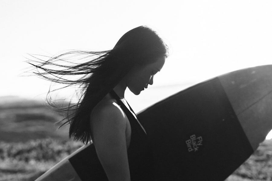 Female surfer with Fly Black Bird surfboard