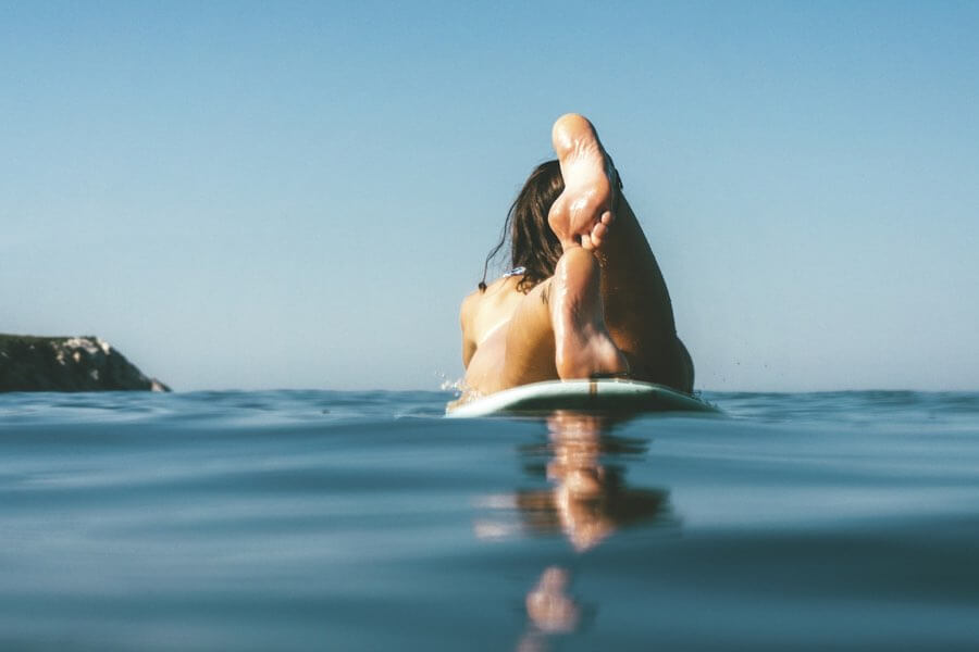 Female surfer laying on surfboard