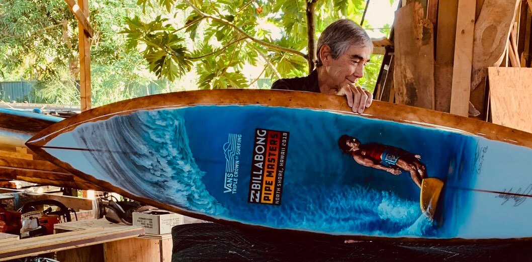Gerry Lopez with a surfboard he shaped featuring art by Phil Roberts