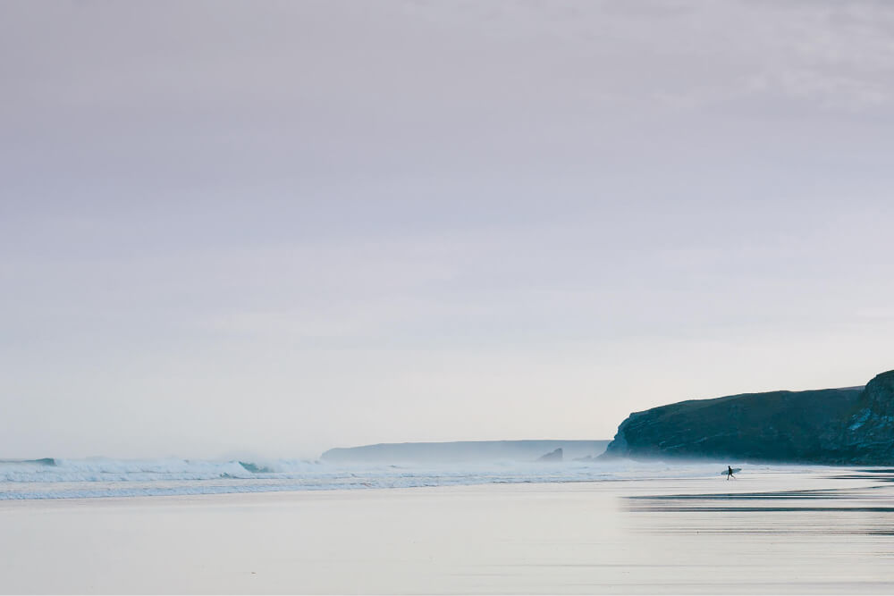 Lone surfer walking on a Cornwall beach