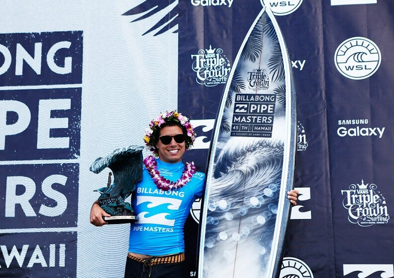 2015 Pipe Masters winner, Adriano de Souza with the Pipe Masters trophy surfboard by Phil Roberts